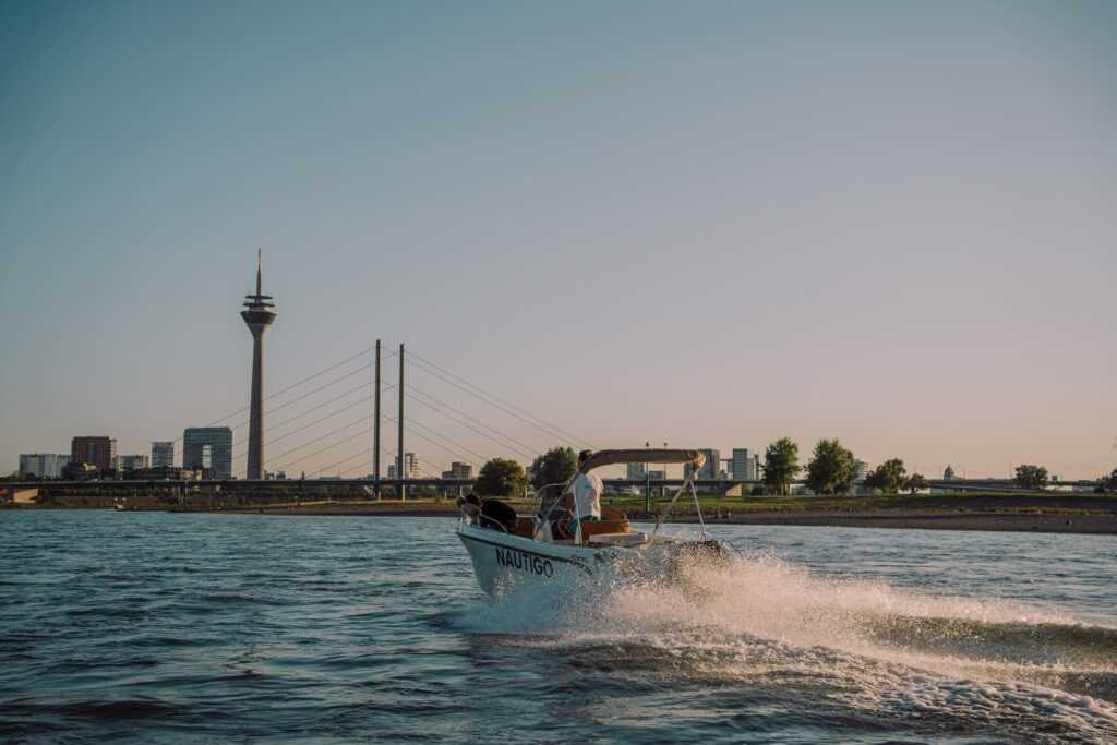 Nautigo-Motorboot auf dem Rhein in Düsseldorf mit Rheinturm und Rheinkniebrücke